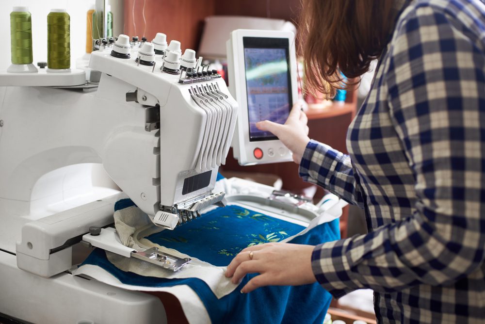 A woman using an electronic machine to embroider.