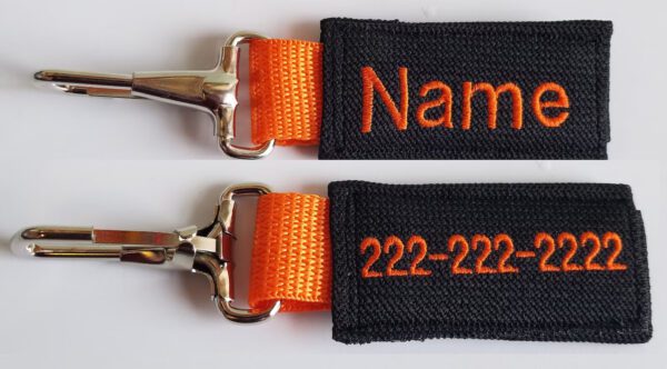 A pair of orange and black key chains with the name, phone number and address on them.