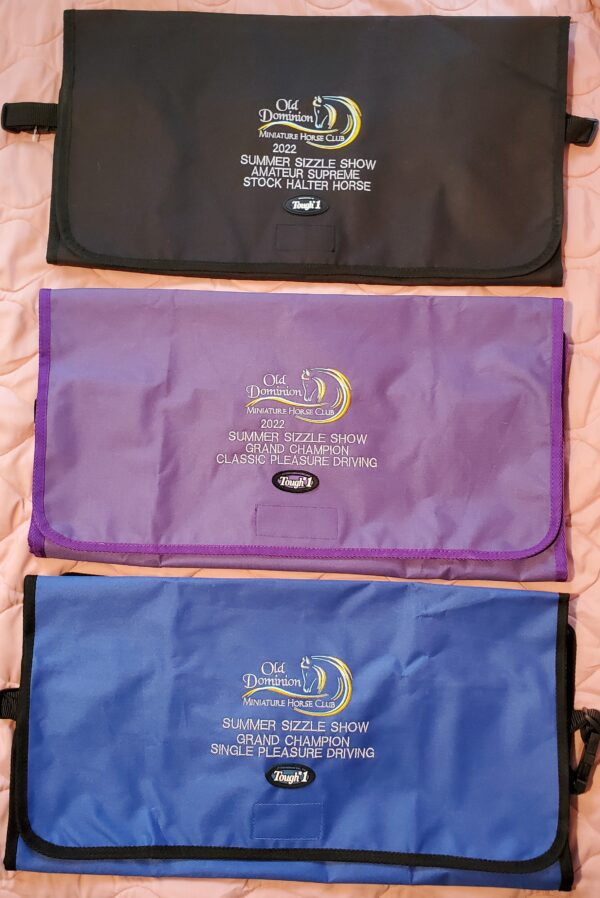 Three bags of various colors and designs on a bed.